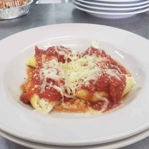 Stuffed pasta shells with marinara and cheese in a shallow bowl
