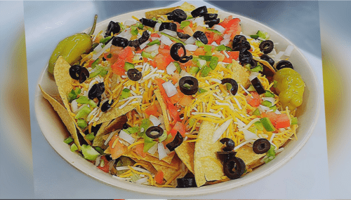Taco salad with black olives, nachos, lettuce, cheddar jack cheese, etc