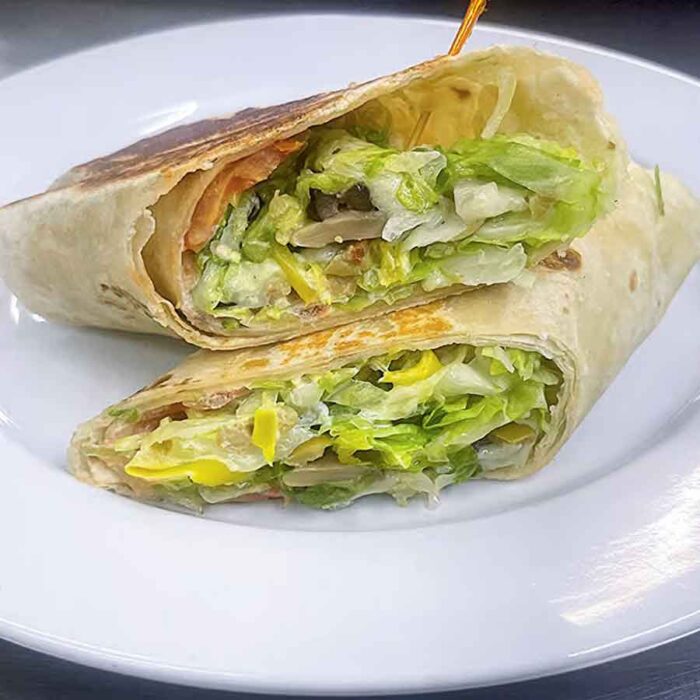 Vegetable wrap with lettuce, Onion, green & banana pepper, green & black olives, mushroom, lettuce, tomato, provolone cheese, mayo on a plate
